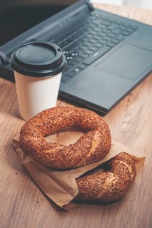 Simits with coffee on a wooden table, with a laptop, in a cozy working environment, snack,