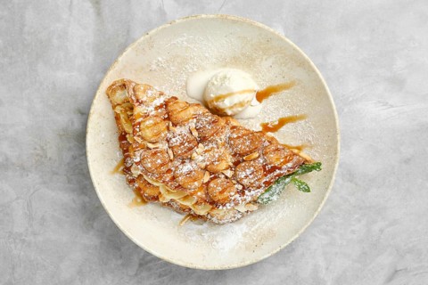 A beautifully plated dessert showcases a crispy pastry filled with caramelized bananas, dusted with