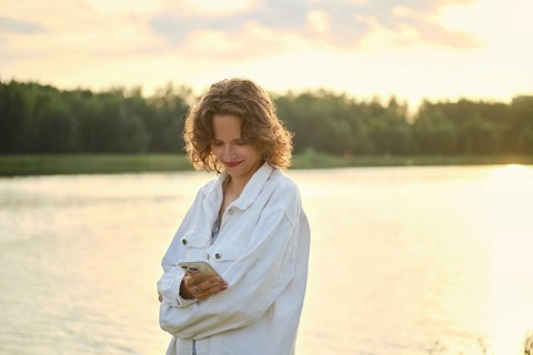 A person stands by the lake on a hot day, enjoying the sunny weather. The golden light creates a