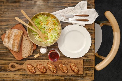 A vibrant salad with greens and corn in a bowl next to a loaf of rustic bread. Savory meat patties