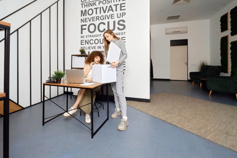 A woman looks into a box with the archives that her colleague brought to modern coworking