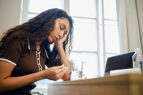 A woman experiences pain during menstruation and is forced to take painkillers while working