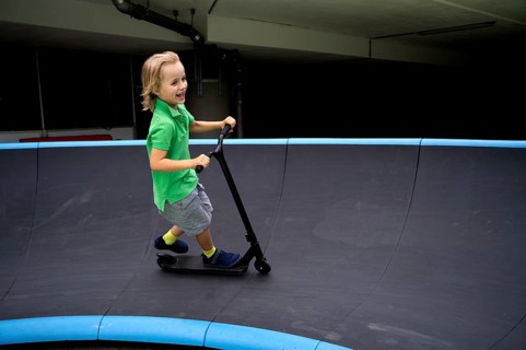 Boy, 6 years, blond, rides scooter, scooter, pump track, laughs, joy, Stuttgart, Baden-Württemberg,
