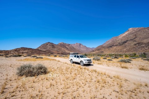 Off-road vehicle on a sandy track, desert landscape with Brandberg, Erongo, Damaraland, Namibia