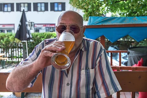 Senior citizen with sunglasses drinking a wheat beer in a beer garden, Upper Bavaria, Germany