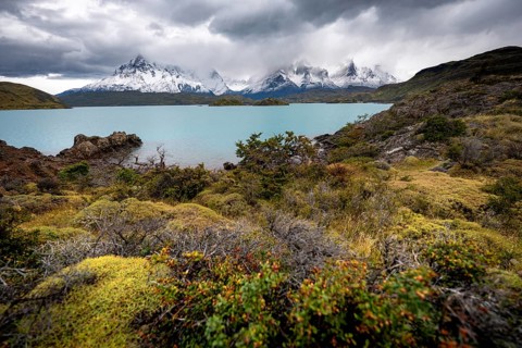 Cloudy mountain range Cuernos del Paine, shore of the blue lake Lago Pehoe in the evening light,