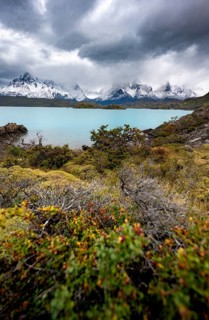 Cloudy mountain range Cuernos del Paine, shore of the blue lake Lago Pehoe in the evening light,
