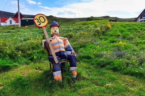 Funny traffic control, 30 km/h, speed limit, figure sits on summer meadow and holds self-made