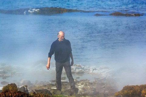 Hot spring flows into the sea, tourist on steaming rocky coast near Reykjanes, Súðavík,