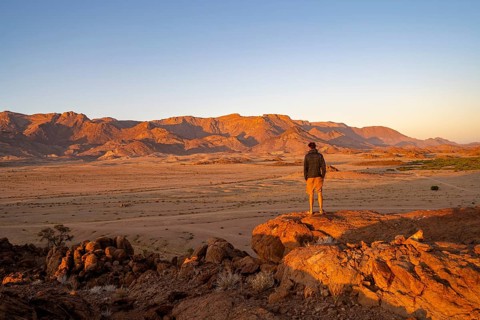 Young man in dry desert landscape, Brandberg in the morning light, at sunrise, Erongo, Damaraland,
