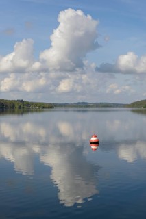 View over the Möhnesee, red and white buoy, blue cloudy sky, reflection on the water surface,