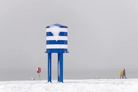 Winter day, onset of winter, snow on the North Sea coast, people walking on the beach promenade of