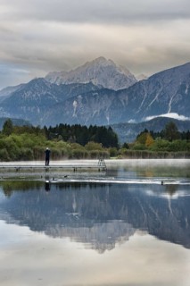 Man (60-70) with dog on a wooden footbridge at sunrise, Hopfensee, near Füssen, Ostallgäu, behind