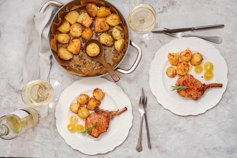 Pork rib roast paired with crispy golden potatoes on white plates. Enjoy this inviting meal set on