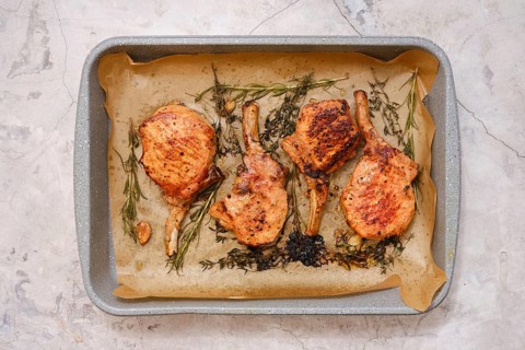 Juicy pork rib roasts are seasoned and cooked to perfection on a baking tray lined with parchment