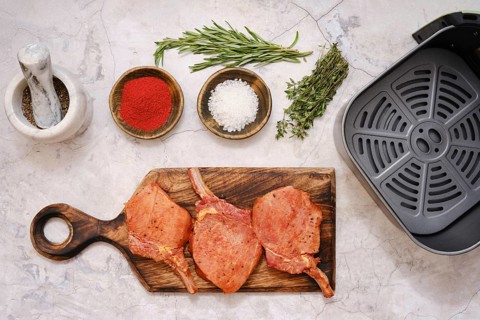 Marinated pork rib roast is seasoned with herbs and spices on a wooden cutting board while being