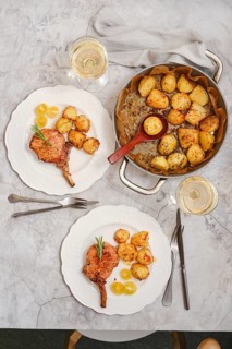 Roasted pork rib roast served alongside beautifully roasted crispy potatoes. The setting features