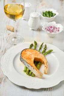 A succulent piece of salmon on a plate with crispy asparagus spears. Accompanying the dish is a