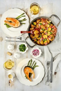 A beautifully arranged dining table features two plates of grilled salmon served with roasted