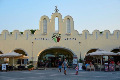 Agora, Municipal market hall, Lively market with white buildings and parasols in the foreground,