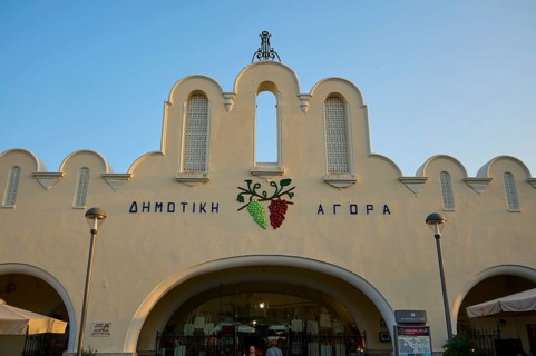 Agora, Municipal Market Hall, White market hall with Greek writing and grape emblem, illuminated by