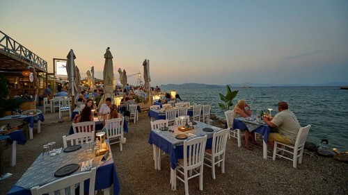 Restaurant at the Turkish ferry harbour, dinner by the water at sunset with white-blue tables and a