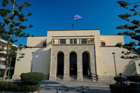 Archaeological Museum, beige building with Greek flag on the roof, symmetrical architecture,