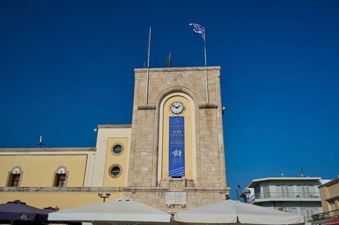 Cinema, Eleftherias Square, Historic clock tower with Greek flag against a clear sky, Kos Town,
