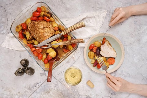 Tender roasted turkey breast rests in a baking dish surrounded by vibrant roasted vegetables. A