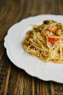 A plate of seafood spaghetti features fresh pasta topped with shrimp, mussels, and vegetables. It