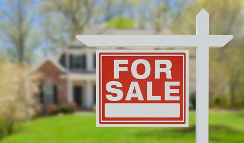 For sale real estate sign in front of beautiful house