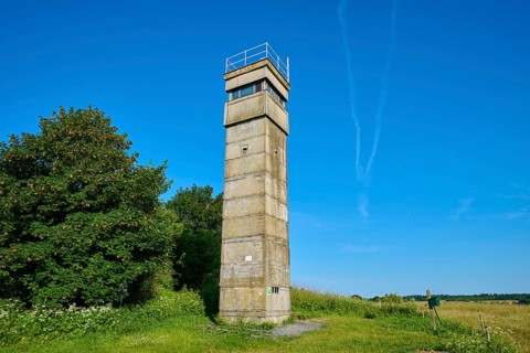 Isolated watchtower of the former inner German border under a cloudless sky next to a green