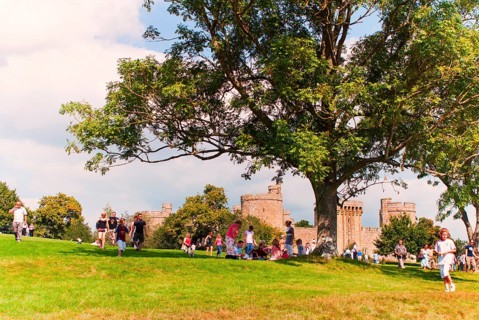 Tourists and locals in front of Bodiam Castle, located in East Sussex near the River Rother. It has