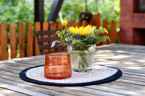 Close up of yellow and purple flower bouquet and storm lamp with candle decoration on table