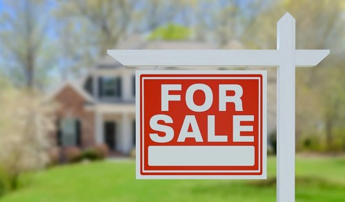 For sale real estate sign in front of beautiful house