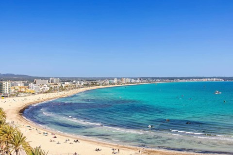 Aerial view at a tourist resort area with sunbathing people on the sand beach by the blue