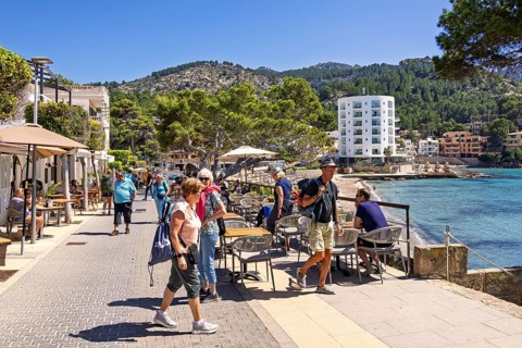 Tourists on a boardwalk and restaurants by the Mediterranean Sea at a tourist resort a sunny summer