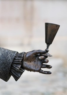 Close-up of hand holding champagne glass, statue of Louis XV in front of Hotel Champagne De Venoge,