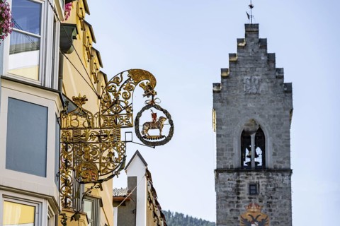 Artistic golden hanging sign, nose sign, old town centre, behind Zwölferturm, Sterzing, South