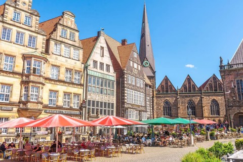 Historic row of buildings with bay windows, gabled houses, pointed tower and nave of Our Lady's