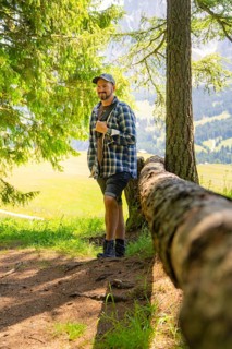 Man leaning against a tree trunk and enjoying the forest atmosphere, Alpe di Siusi, Dolomites,