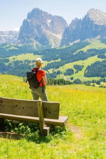 Person looking from a bench at the impressive mountain landscape, Alpe di Siusi, Dolomites, South