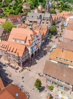 Aerial view of a half-timbered town with church and market square during a busy summer day, 950