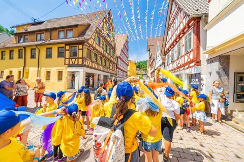 Children in yellow T-shirts and blue caps at a street parade in summer. Festive atmosphere with