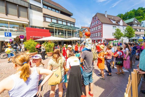 Crowds of people in the town in sunny weather, surrounded by half-timbered houses and modern