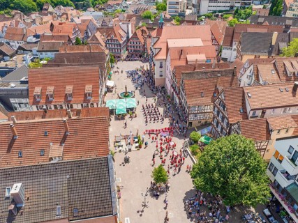 Aerial view of a historic town centre with an event and traditional architecture, 950 years of