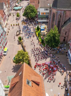 Aerial view of a celebration in a historic town with half-timbered architecture and many people,