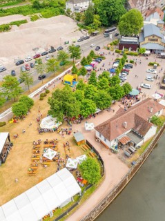 Aerial view of people at an event on a green area, surrounded by trees and river, 950 years Calw,