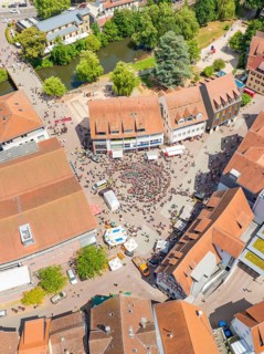 Aerial view shows a dense cityscape with people on a square, surrounded by buildings and trees, 950