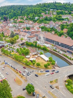 Cityscape with crossroads, cars and a large Ferris wheel along a river, 950 years of Calw, Calw